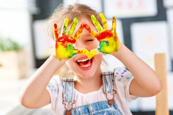 happy funny child girl draws laughing shows hands dirty with paint